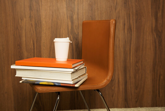 Books stacked on chair with coffee cup in study area 