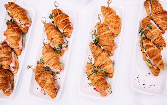 Croissants filled with various ingredients on white platters