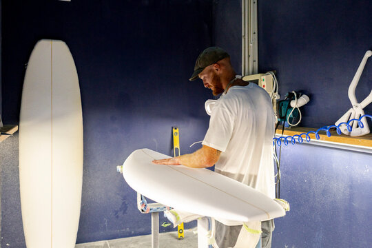 Surfboard shaper checking blank by hand 