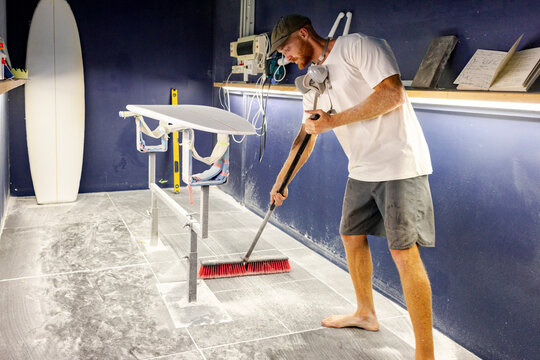 Surfboard shaper sweeping shaping bay in Australia