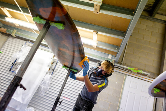 Shaper glassing surfboard rail in Australia