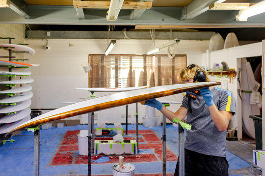 Shaper inspecting glassed surfboard in Australia