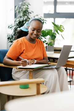 Woman Works on a Laptop and Takes Notes in a Bright Office