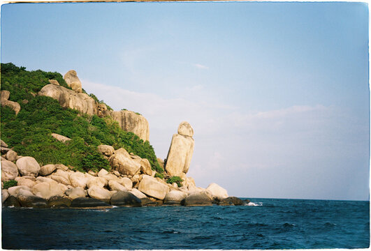 Large rock formation stands on the coast near the water