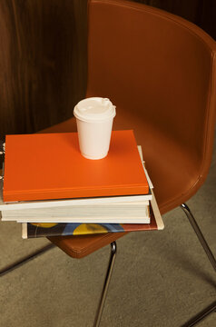 Books stacked on chair with coffee cup in study area 