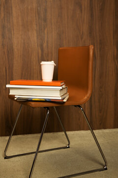 Books stacked on chair with coffee cup in study area 