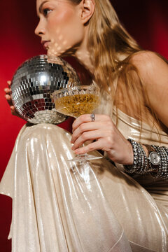 Woman Holding Cocktail Glass and Mirror Ball in Shimmering Dress