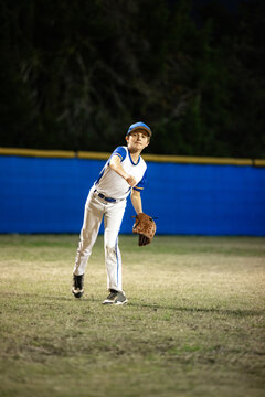 Young Baseball Player Throws Ball on Diamond at Night