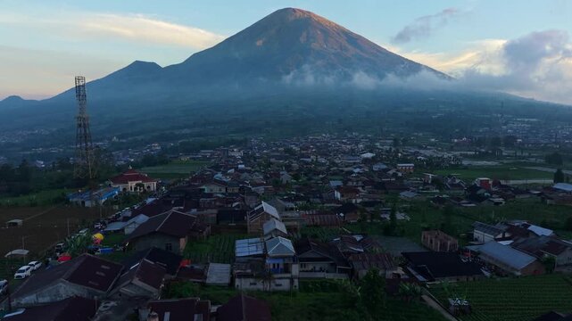 Aerial view of Mount Sindoro volcano towering over the village of Garung and Kecamatan Kalikajar with soft morning light, Kecamatan Kalikajar, Jawa Tengah, Indonesia.