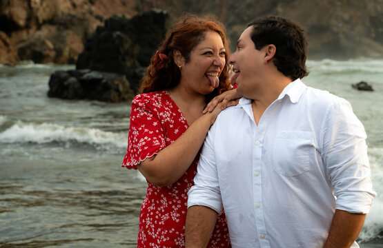 candid Young Couple Laughing Together on Beach at Sunset