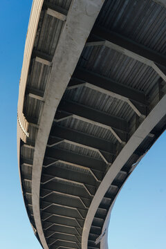 Underside of modern concrete bridge structure against blue sky