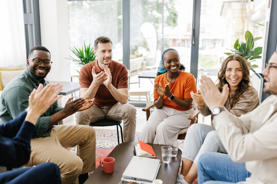 Group of People Clapping and Smiling During a Meeting in a Bright Room
