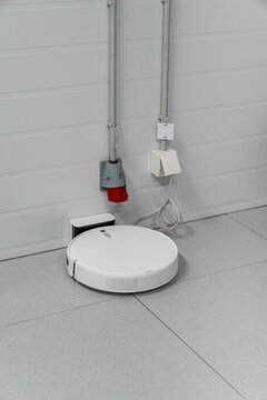 Robot vacuum cleaner charging at wall dock with electrical outlets