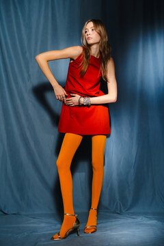 Woman in Red Mini Dress and Yellow Tights Adjusting Dress in Studio