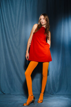 Woman in Red Mini Dress and Yellow Tights Standing in Studio Pose