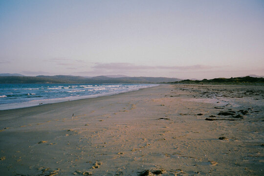 Sandy beach in Tasmania with blue mountains in the distance 