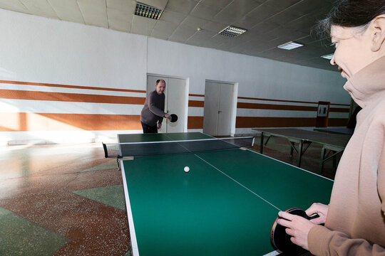 A woman and a man are playing table tennis.