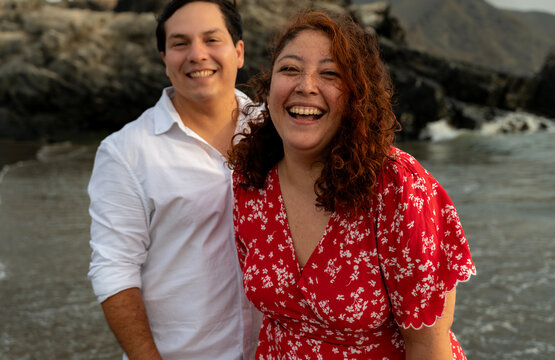 candid Young Couple Laughing Together on Beach at Sunset