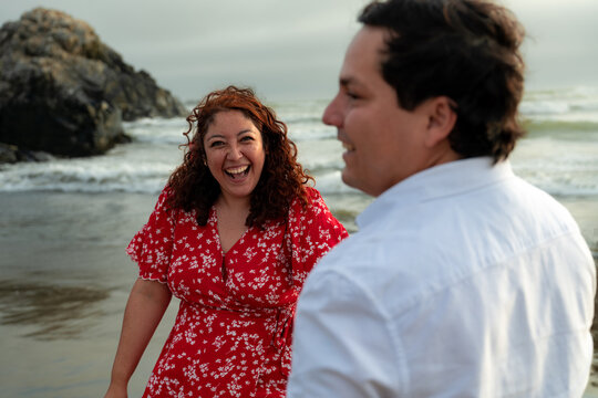 candid Young Couple Laughing Together on Beach at Sunset