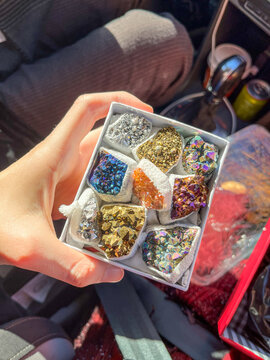 Hand Holding Gift Box with Colorful Crystal Stones Inside Car