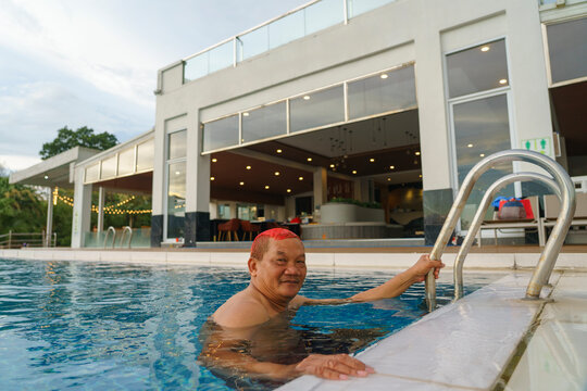 A middle-aged man enjoys swimming at an infinity pool inside a resort