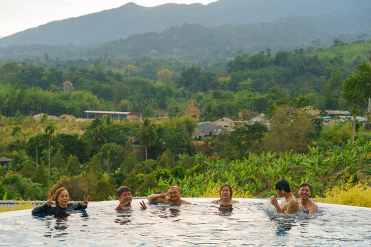 Friends enjoying their time at infinity pool with nature in background
