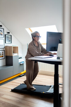 Senior woman balancing work and wellness with treadmill desk