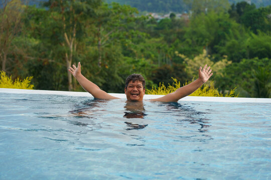 Adult plus-size man enjoy swimming at infinity pool with a nature view