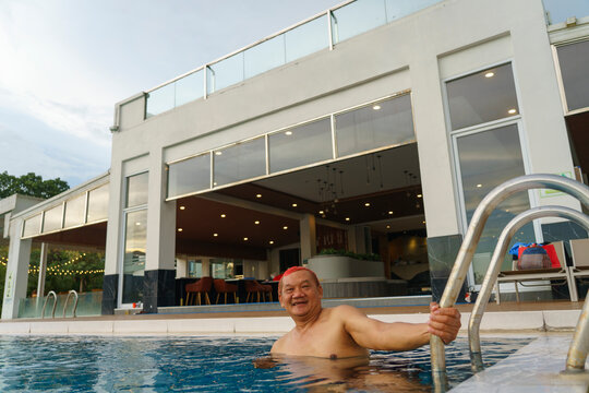 A middle-aged man enjoys swimming at an infinity pool inside a resort