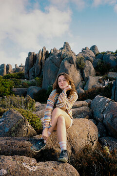 Woman sits among the weathered rocks in Tasmania, Australia 
