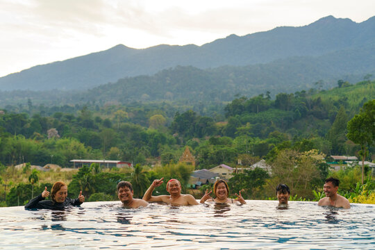 Friends enjoying their time at infinity pool with nature in background