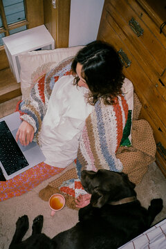 Woman sitting on a floor with the dog and working with laptop 