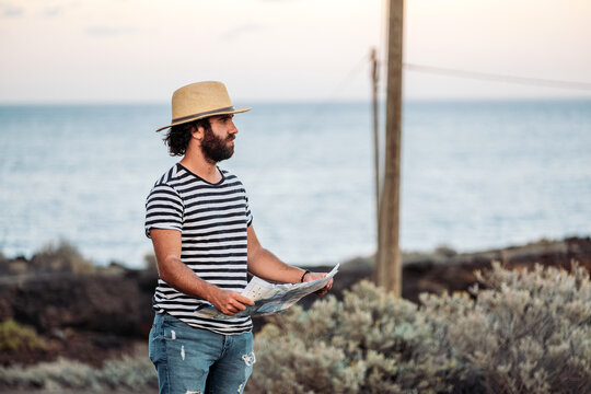 Bearded man holding map exploring coastal travel journey