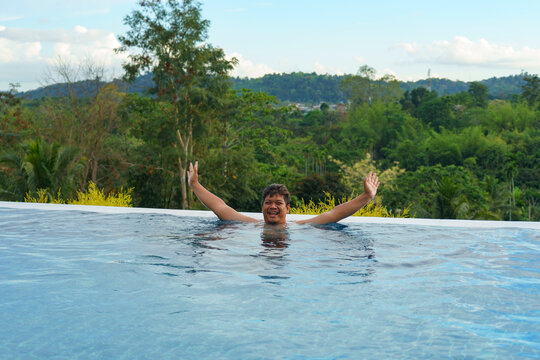 Adult plus-size man enjoy swimming at infinity pool with a nature view