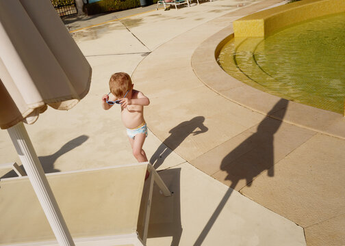 Child Playing Near Pool in Summer Sunshine at a Resort