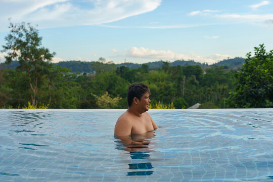 Adult plus-size man enjoy swimming at infinity pool with a nature view