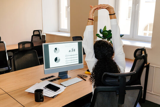 Businesswoman Stretching Arms While Sitting at Office Desk