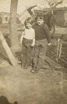 Children posing arm in arm next to fence