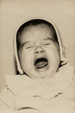 Crying baby wearing bonnet in vintage style