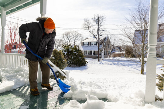 Portrait senior man snow shovel porch home