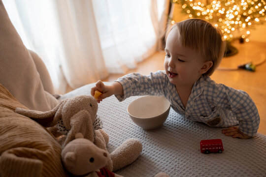 Toddler feeding stuffed toy rabbit during pretend play on sofa at home