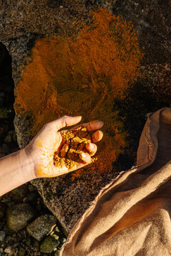 Hand holding pigment for dyeing fabric in natural stone setting