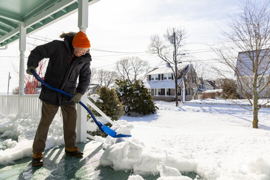Portrait senior man snow shovel porch house