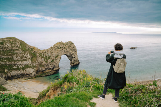 Woman taking a photo of Durdle Door, Dorset in UK 