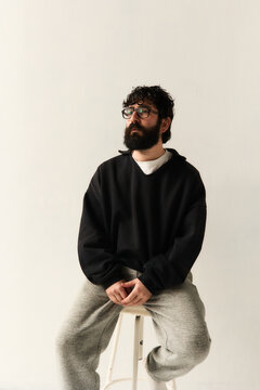 Bearded man sitting on chair against white wall