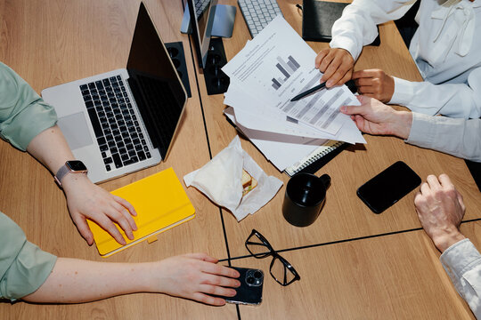 Colleagues Analyzing Business Reports at Office Desk During Meeting