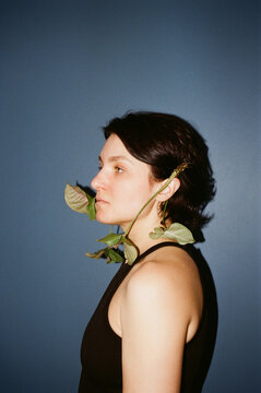 Woman with leaves on her ears poses against blue wall