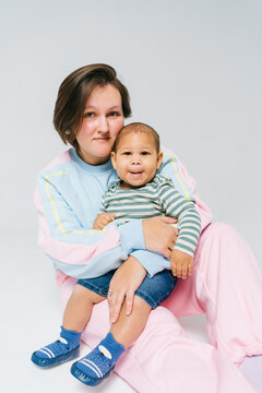 A mother sits with a small child in a bright studio.