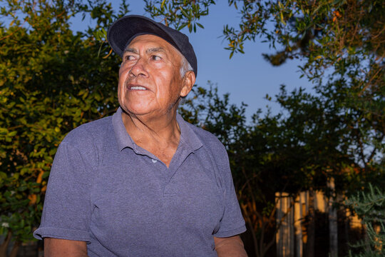 Latino farm worker in cap looking away outdoors