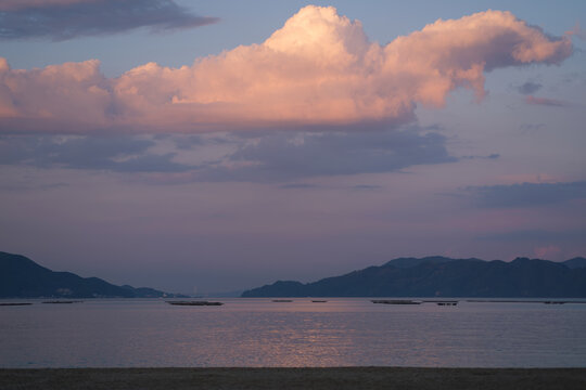 大浦崎海岸の夕暮れ時にピンク色に染まる雲と静かな海の風景（広島県呉市）